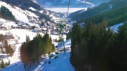 The Schmittenhohenbahn cableway overlooks the stunning nature of Zell am See resort, frozen Zeller see (lake) in valley, tall fir trees and ski trails, Austria.