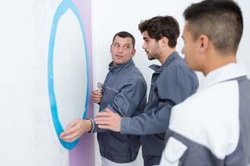man showing apprentices how to paint a wall