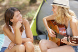 women playing the guitar in a tent on the nature
