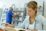 young student woman reading a book in library
