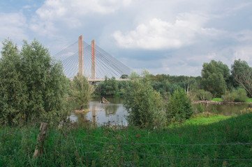 orange suspension, wire bridge Zaltbommel, called Martinus Nijhoff brug, The Netherlands. with trees and ditch
