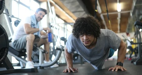 Portrait of a handsome man doing push ups exercise in gym