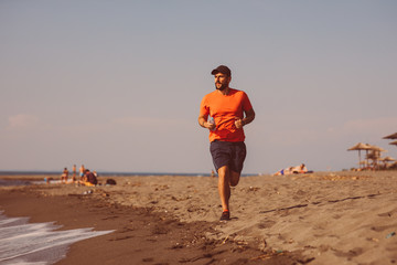 Young man jogging on the beach by the sea