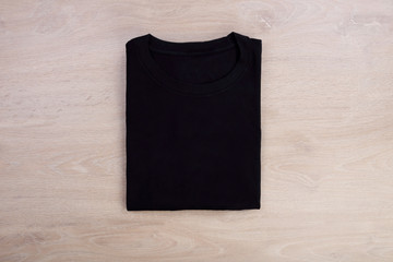 Top view folded black t-shirt mockup on wooden background