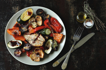 Baked vegetables and fruits with sesame on the plate. Vegan food. Healthy diet. Shabby background. Stylish vegan lunch.