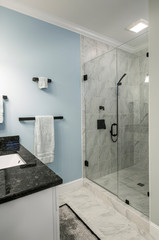 Modern bathroom with glass shower and marble tile and blue wall.