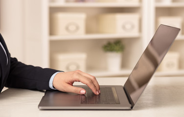 Business woman below chest working on her laptop in a cozy environment

