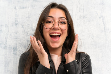 Teenager girl over grunge wall with surprise facial expression