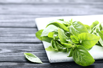 Green basil leafs with cutting board on black wooden table