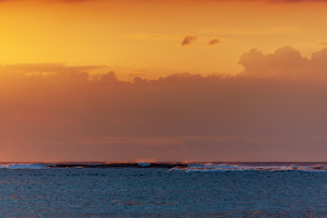 Ocean surf on teh burning sunset background on Mauritius island seashore