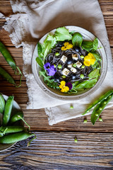 Black bean pasta salad with leafy greens, olives, green peas, sheep cheese and edible flowers