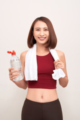 Sporty girl with bottle of water and towel on her shoulders on light background