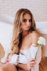 Photo session of a young girl in a bathroom with a white rose in her hand. The girl in the bikini.