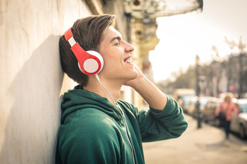 Teenager standing in the street, listening music with headphones