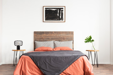White minimal bedroom with wooden headboard and coral and grey bedsheets