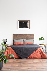 Minimal bedroom with wooden bed, plants and painting