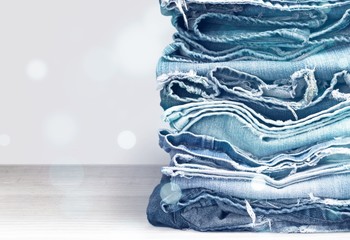 Stack of jeans clothes on background