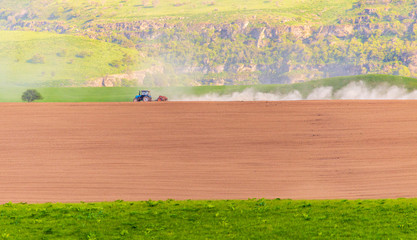 Dust from a tractor working in a field in spring