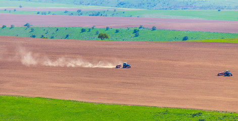 Dust from a tractor working in a field in spring