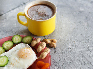 Sandwich with fried egg, nuts, dried apricots and cucumber and a Cup of coffee on a concrete background
