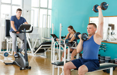 Positive man doing exercises with dumbbells