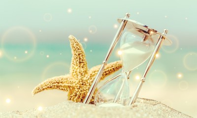 Hourglass and seastar on sandy beach