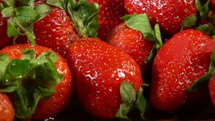 Strawberry on wooden table, bedabbled with dew and leaved. Pile of picked freshly red berry and green leaves with vertical motion . There is place for inscription.