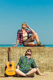 Young man playing guitar to his girlfriend by seaside