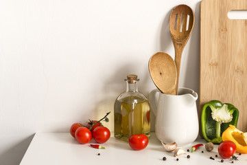 Wooden Kitchenware, olive oil and vegetables on table wall background. Template for text