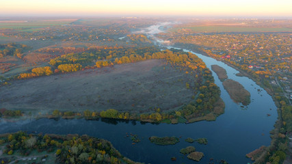 Aerial view of river and autumn trees in the early foggy morning
