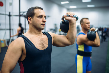 Athletes with weights in gym, kettlebell lifting