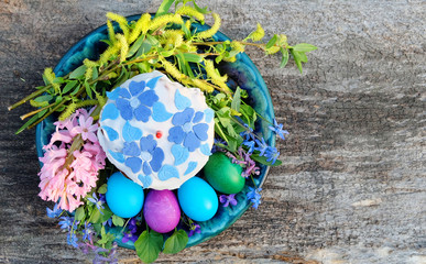 Easter cake with a candle, painted eggs, spring flowers. Easter composition on the old wooden table, top view.