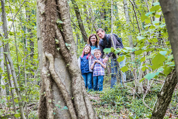family with two children smile while taking a trip in the woods