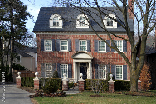 "two storey brick house with dormers, shutters, and hedge ...