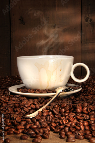 Fototapeta White coffee cup with spoon on roasted beans