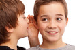 Zwei Jungen flÃ¼stern sich News und Geheimnisse ins Ohr