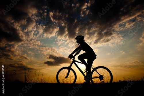  Biker-girl at the sunset on the meadow