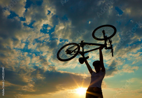 Fototapeta Biker holds bike high up in the sky