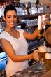 Attractive bartender tapping beer in bar