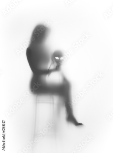 Lacobel Beautiful woman sits on chair with mask behind a glass surface