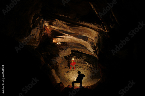 Fototapeta Spelunkers exploring an underground cave