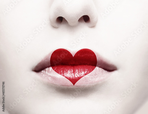 Fototapeta Close up of female lips with red heart shape painted on it