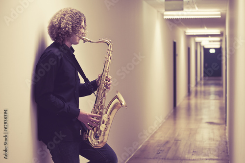 Fototapeta Man playing the saxophone in a hallway
