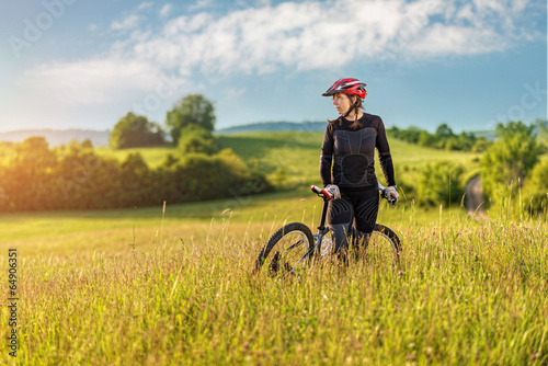 Fototapeta Sport bike woman relaxing on a meadow, beautiful landscape