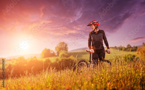 Fototapeta Sport bike woman relaxing on a meadow, beautiful landscape