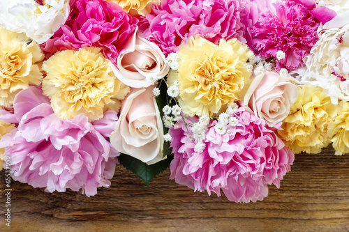 Fototapeta Stunning pink peonies, yellow carnations and roses on rustic