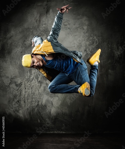  Man dancer in cap and jacket showing break-dancing moves