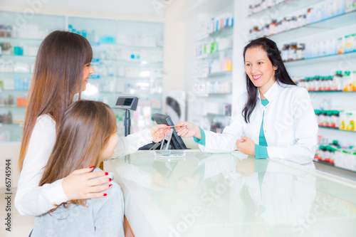 pharmacist giving vitamins to child girl in pharmacy drugstore