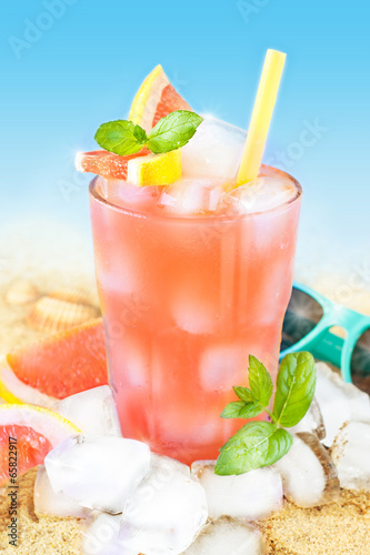  Cold grapefruit juice with ice on beach background