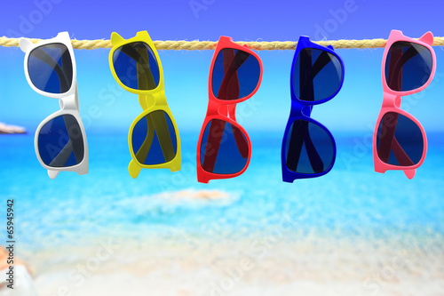 Lacobel Colorful Sunglasses hanging on a rope in front of the sea
